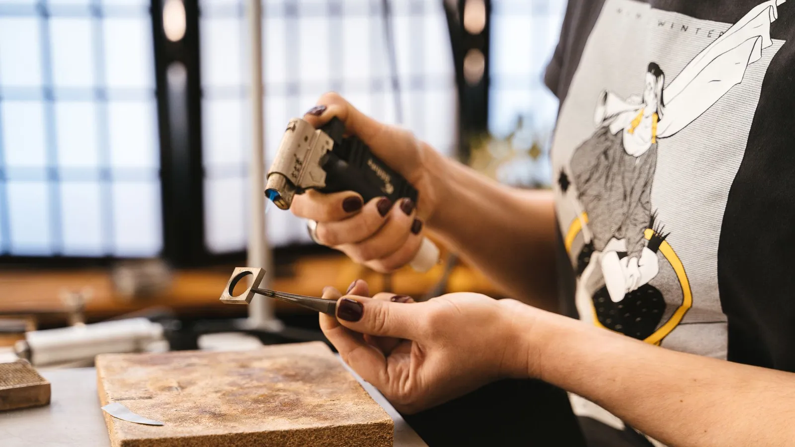 Créatrice de bijoux ajustant une bague à l'établi de son atelier, outils de précision en main