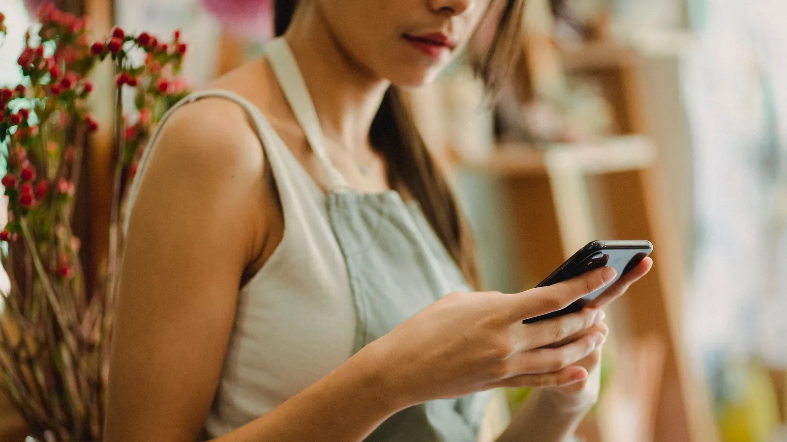 Créatrice consultant ses messages sur son téléphone entre deux commandes dans sa boutique