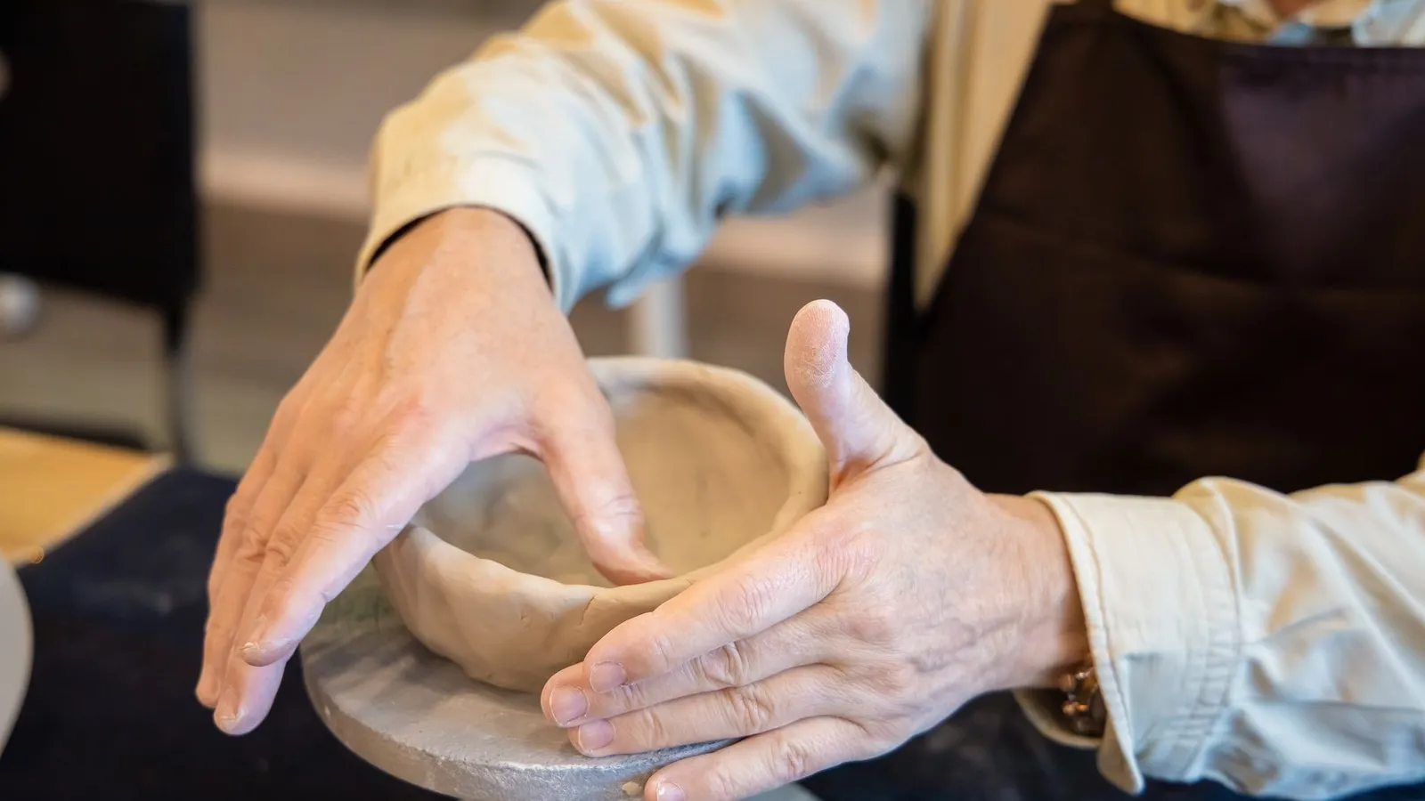 Mains façonnant un bol en argile sur un tour de potier, geste précis d'artisanat céramique